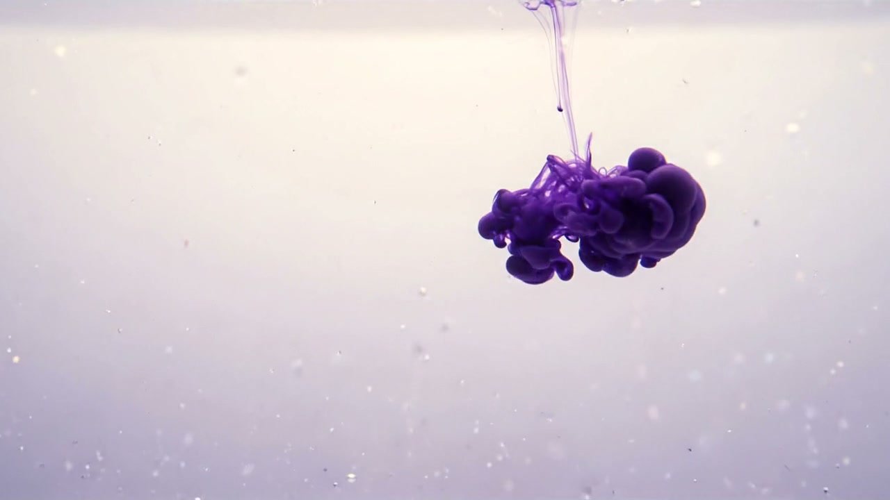 A drop of violet ink opening into soft plumes in still, pale water